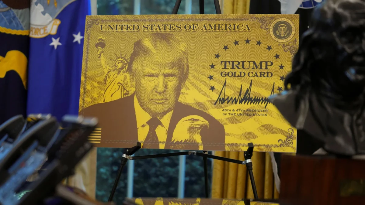 A sign displaying an image of U.S. President Donald Trump with the text "Trump Gold Card" is seen in the Oval Office at the White House in Washington, D.C., U.S., September 19, 2025. (Ken Cedeno | Reuters)