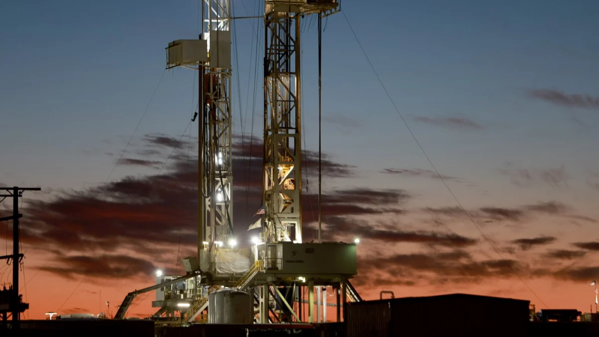 An oil drilling rig operates in the Permian Basin near Midland, Texas. Major oil companies are currently signaling a preference for steady production over significant increases, even as global oil prices rise.