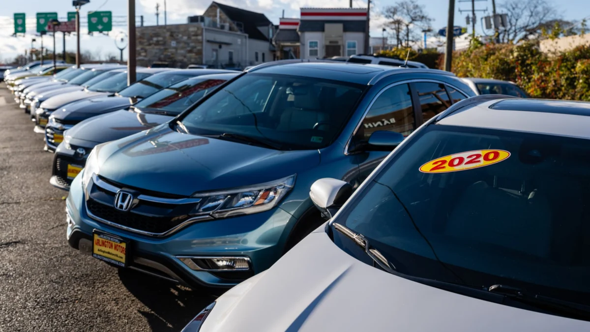 A dealership lot with a mix of new and used cars illustrates the ongoing price pressures in a tightened market.