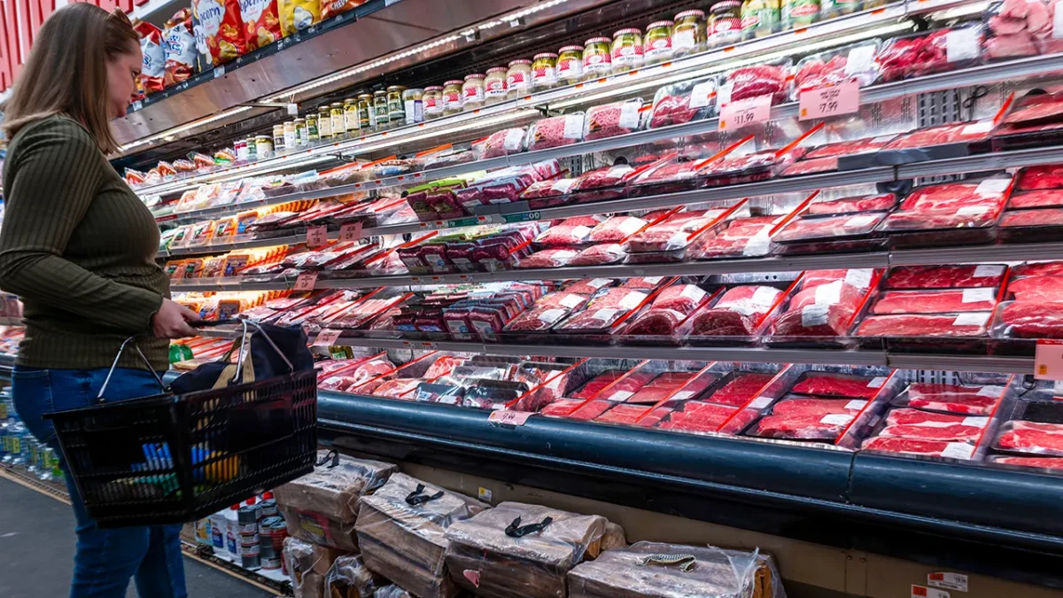 A grocery store display shows prices rising for burgers, sides, and produce as inflation bites into summer cookouts.
